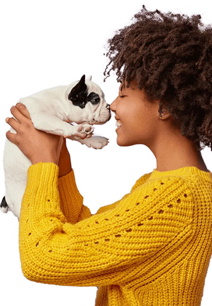Woman in a yellow sweater holding up a small black and white dog